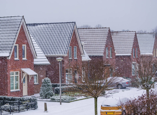 寒い冬の日の間に近代的なオランダの近所、オランダの村の通りで雪の天気 - 写真・画像