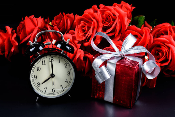 Alarm clock, Gift box, bag and red rose on black background. Concept of Valentine's day - Photo, image