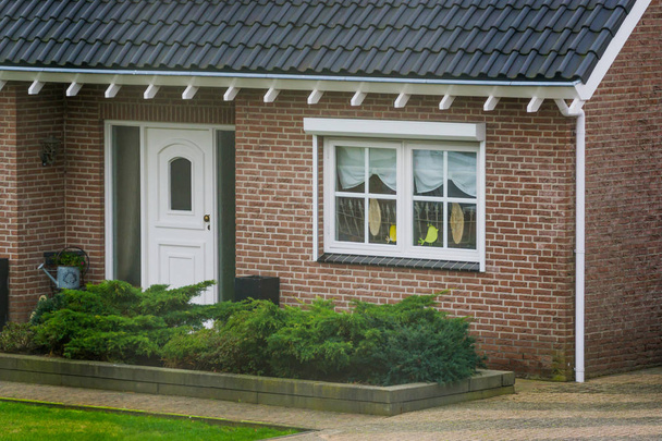 Lüks bir Hollanda bungalovunun ön cephesi. Bahçesi, penceresi dekore edilmiş ön kapısı, Hollanda 'nın küçük bir köyünde evi var. - Fotoğraf, Görsel