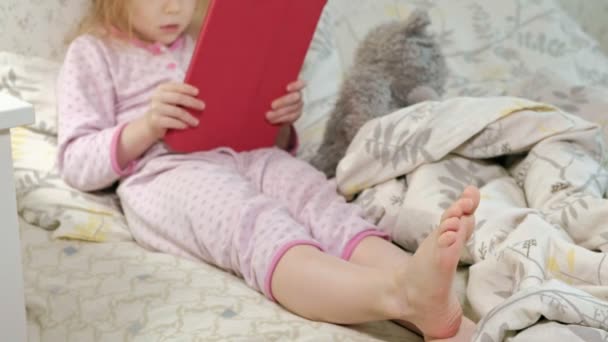 little girl in bed playing on tablet - Felvétel, videó