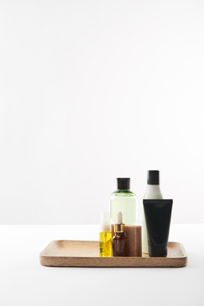 Bandeja de madera con varios recipientes cosméticos y jabón en la superficie blanca
 - Foto, Imagen