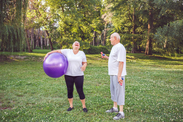 кардио упражнения для пожилых - счастливая пожилая женщина с фитнес-мячи в парке и упражнения
 - Фото, изображение