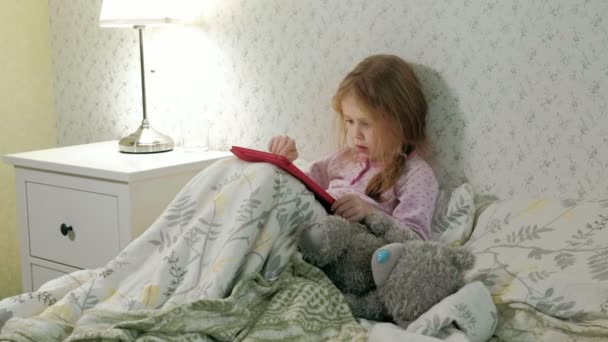 pieni tyttö sängyssä leikkii tabletilla
 - Materiaali, video