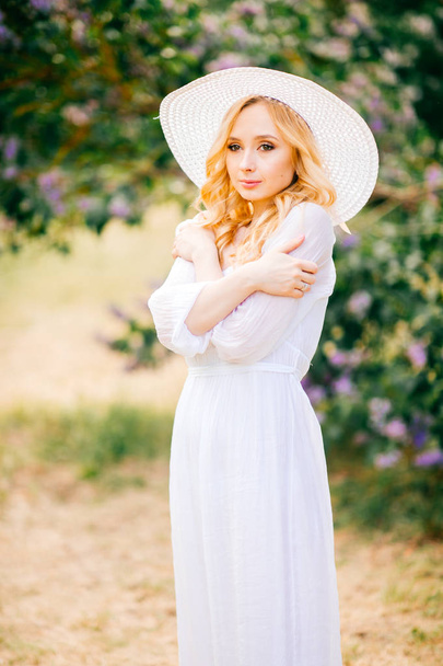 Young beautiful woman in white dress posing in spring blooming garden - Fotografie, Obrázek