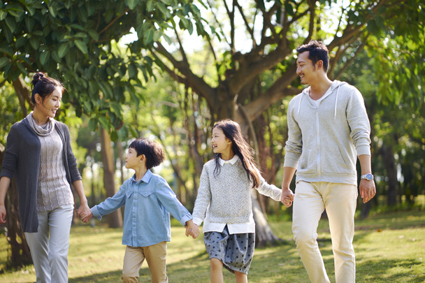 幸せと笑顔の公園でリラックスを歩く 2 人の子供を持つアジアの家族. - 写真・画像