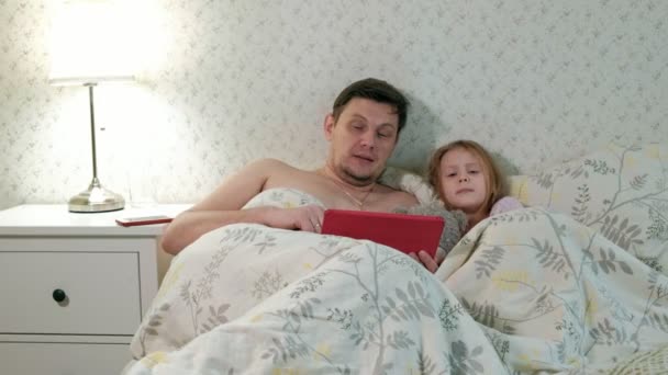 padre e hija pequeña en la cama jugando en la tableta
 - Imágenes, Vídeo