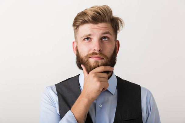 Image of a handsome thinking young bearded man standing isolated over white wall background. - Fotografie, Obrázek