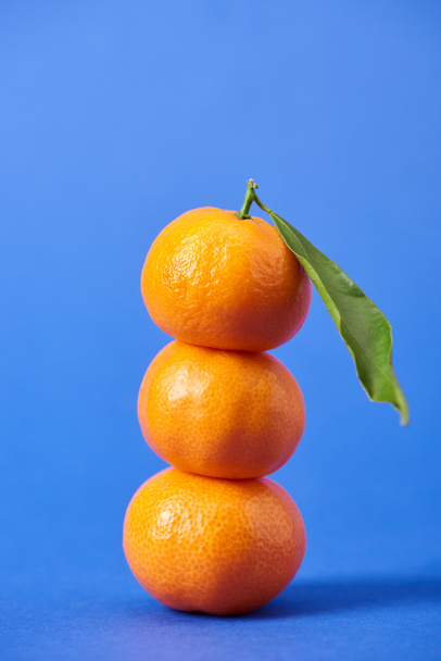 juicy organic tangerines with zest and green leaf on blue background  - Zdjęcie, obraz