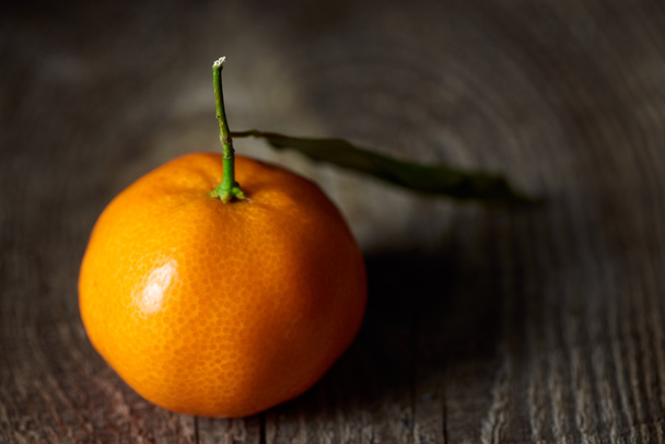 selective focus of fresh tangerine with green leaf on wooden table  - 写真・画像