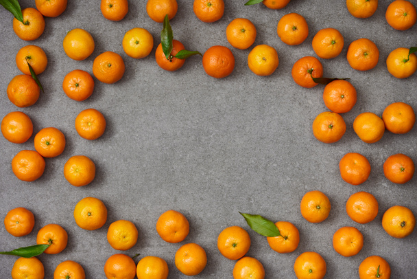 top view of sweet organic tangerines with green leaves on grey table - Φωτογραφία, εικόνα