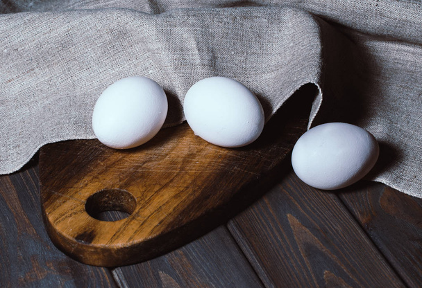 Valkoinen kana pääsiäismunia taustalla vanha puinen pöytä ja leikkuulauta. Terveellinen ruoka ja aamiainen
 - Valokuva, kuva