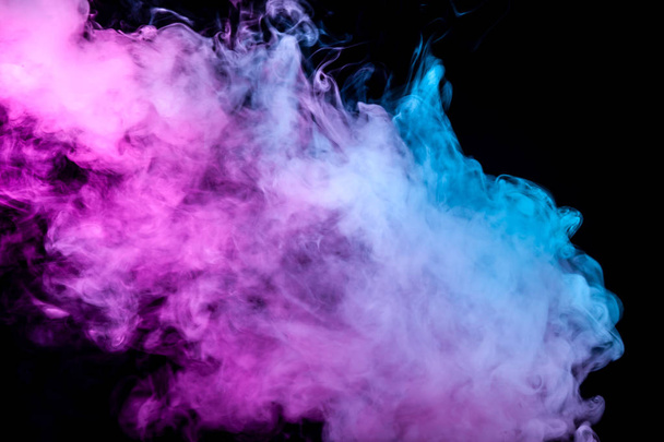 Una spessa colonna di fumo da una coppia di vaporizzatori su uno sfondo scuro, illuminata da neon blu e viola
. - Foto, immagini