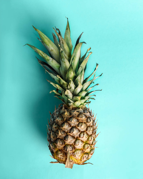 Вид зверху на ананас на ретро яскраво-блакитному тлі. Модний літній однотонний тропічний дизайн над головою. Яскраве пастельне компонування з плодами ананасів зверху. Креативна екзотична їжа
. - Фото, зображення