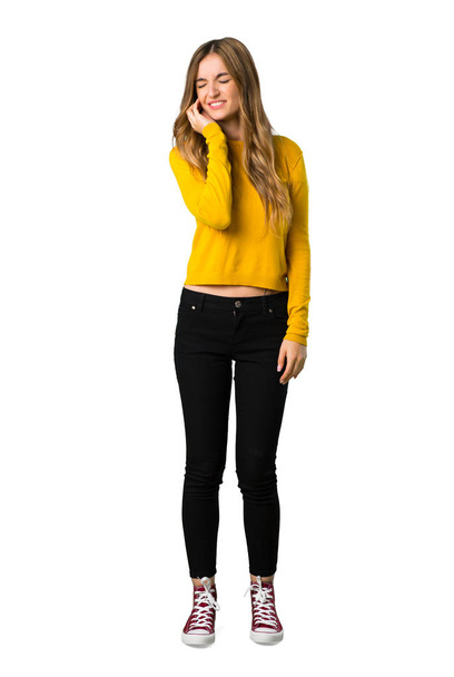 A full-length shot of a young girl with yellow sweater with toothache on isolated white background - Foto, imagen