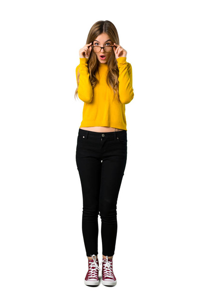 Täyspitkä kuva nuoresta tytöstä, jolla on keltainen pusero, jolla on lasit ja joka on yllättynyt eristetystä valkoisesta taustasta
 - Valokuva, kuva