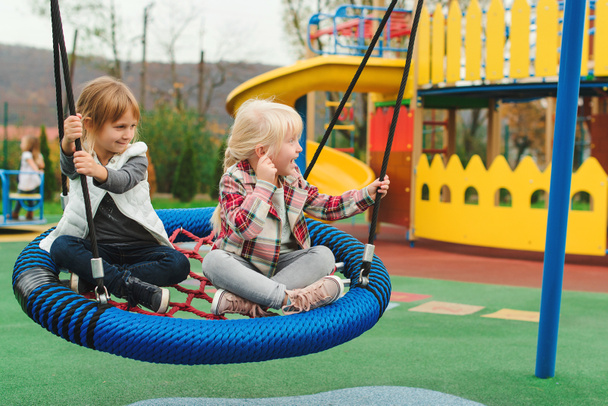 Счастливые дети веселятся на детской площадке под открытым небом. Лучшие подруги играют вместе
 - Фото, изображение