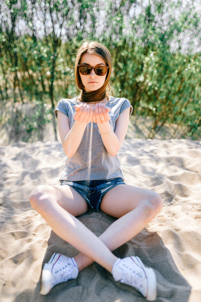 Young girl in casual clothing sitting on sand on beach in summer - Foto, immagini