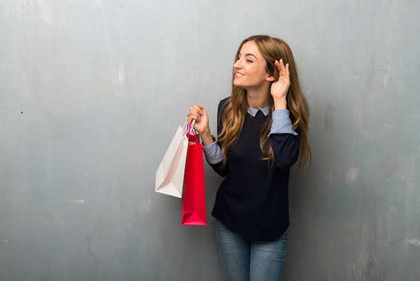 Alışveriş torbaları için bir şey kulak el koyarak dinleme kızla - Fotoğraf, Görsel