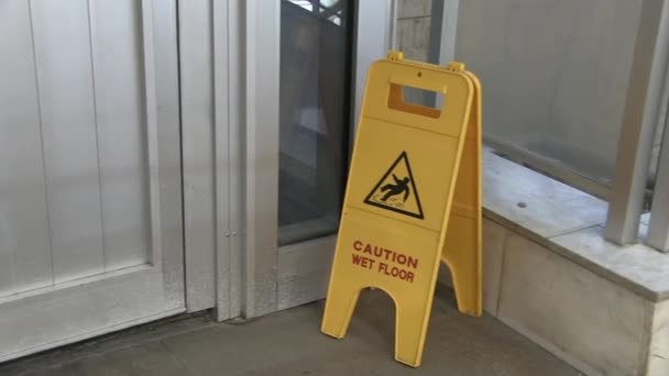 Señal que muestra el icono de advertencia del suelo mojado. Letrero amarillo de pie sobre superficie de hormigón. Sala de exposiciones aviso de precaución
 - Metraje, vídeo