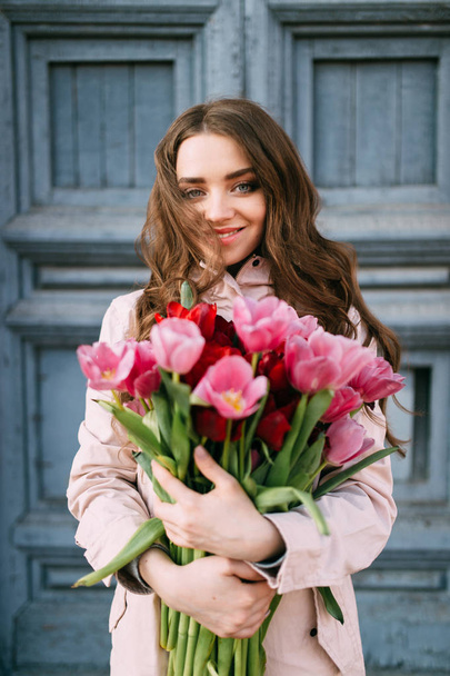beautiful young woman with bouquet of tulips posing on street - Fotografie, Obrázek
