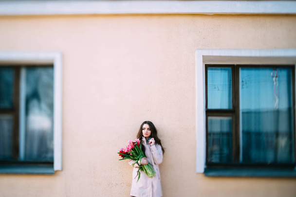 beautiful young woman with bouquet of tulips posing on street - Photo, Image