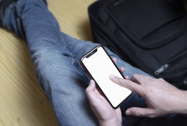 Student auf dem Boden sitzend, sein Handy in der Hand. An seiner Seite ist sein Rucksack - Foto, Bild