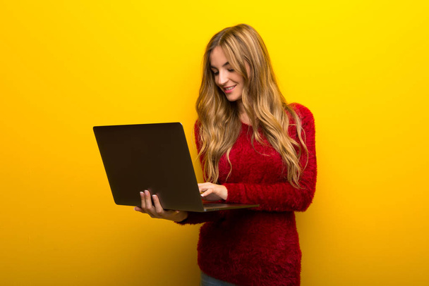 ノート パソコンと鮮やかな黄色の背景に若い女の子 - 写真・画像
