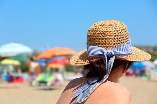 mooi meisje met stro hoed tans op het zee-strand in de zomer - Foto, afbeelding