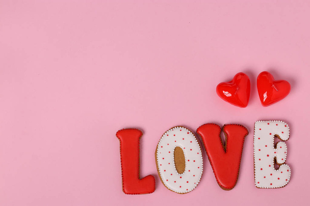 Kotitekoinen piparkakku kirjaimilla "rakkaus" Ystävänpäivä sijaitsee vaaleanpunaisella taustalla, ylhäältä, kopioi tilaa
 - Valokuva, kuva