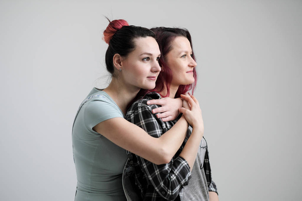 Two girls hug on a white background. Homosexual lesbian couple. Casual clothes. - Фото, зображення