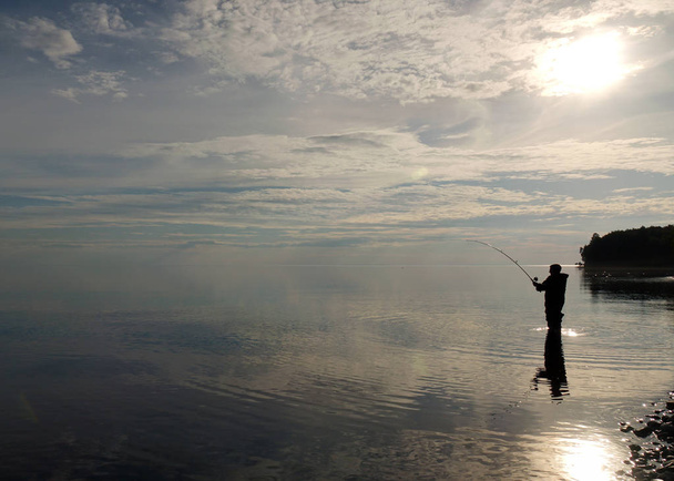 Silhouette di un pescatore al tramonto. Pesca sul lago
. - Foto, immagini