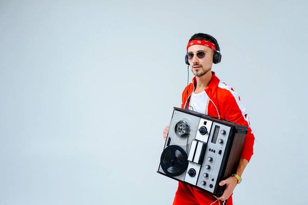 cheerful fashionable man wearing a red sports suit dancing jumps with a retro tape recorder. interesting and fervent style of the 90s. - Photo, Image
