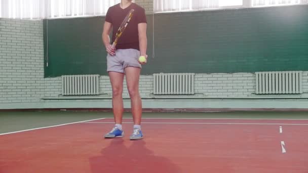 テニスコートでトレーニング。若い男が空中でボールを投げるし、それをヒット - 映像、動画