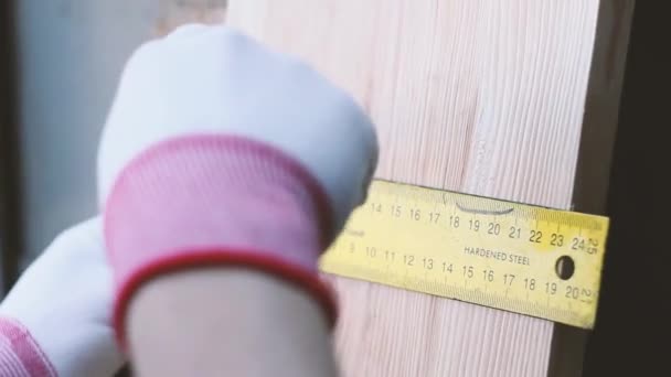 Close up carpenter measures wooden desk with yellow tape measure at workshop. Man in white gloves - Footage, Video