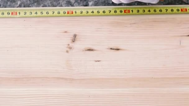 Közelről carpenter intézkedések fából készült íróasztal sárga mérőszalag workshop. Férfi fehér kesztyű - Felvétel, videó