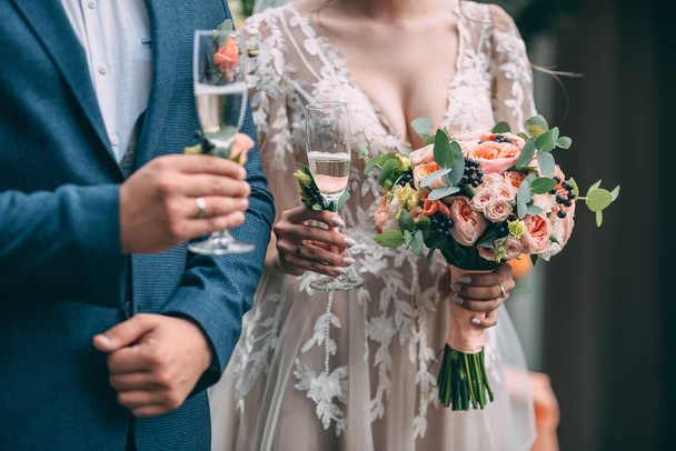 Braut und Bräutigam halten Hochzeitsbrille und stehen auf dem Hintergrund des Hochzeitsbogens, auf der Sandzeremonie. - Foto, Bild
