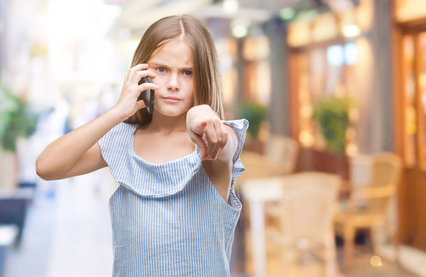 Young beautiful girl talking on the phone over isolated background pointing with finger to the camera and to you, hand sign, positive and confident gesture from the front - Fotografie, Obrázek