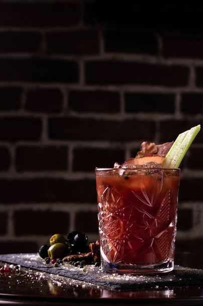 Bloody mary cocktail garnished with celery sticks, bacon and olives. - Photo, Image