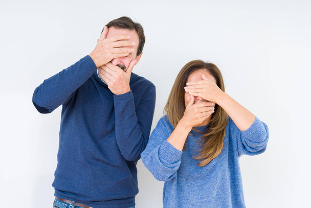Beautiful middle age couple in love over isolated background Covering eyes and mouth with hands, surprised and shocked. Hiding emotion - Zdjęcie, obraz