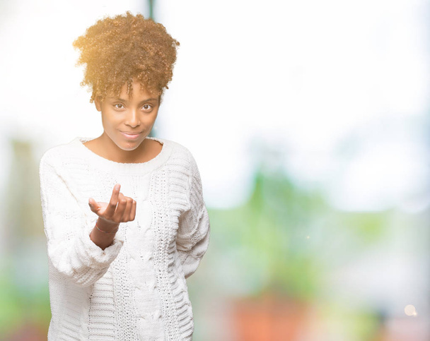 Bella giovane donna afro-americana che indossa maglione invernale su sfondo isolato Beckoning venire qui gesto con mano invitante felice e sorridente
 - Foto, immagini