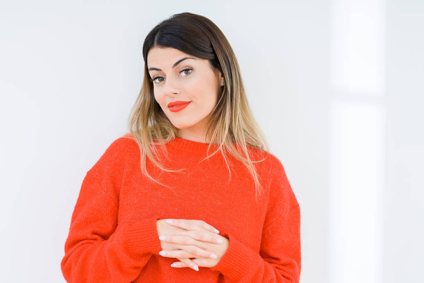 Young woman wearing casual red sweater over isolated background Hands together and fingers crossed smiling relaxed and cheerful. Success and optimistic - Photo, Image