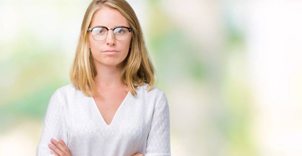 Beautiful young woman wearing glasses over isolated background skeptic and nervous, disapproving expression on face with crossed arms. Negative person. - Photo, Image