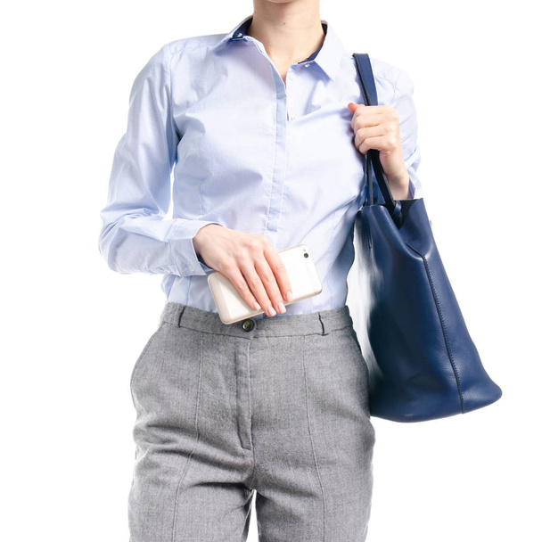 Woman in gray pants and blue shirt blue bag smartphone in hand macro - Foto, afbeelding