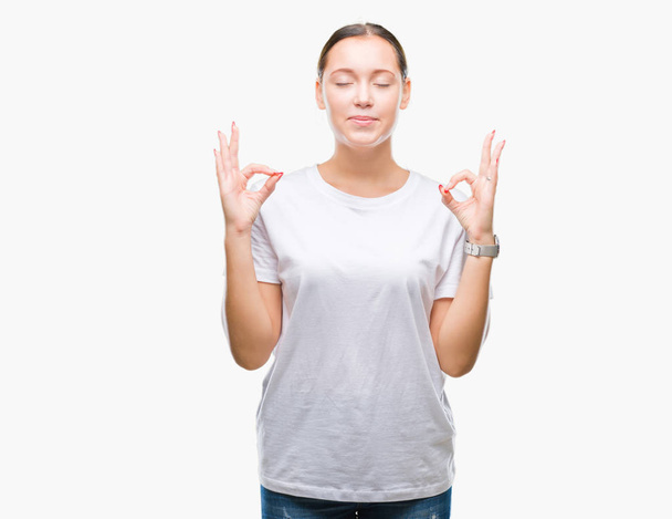 Young beautiful caucasian woman over isolated background relax and smiling with eyes closed doing meditation gesture with fingers. Yoga concept. - Fotó, kép