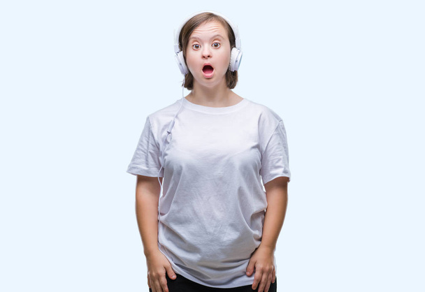 Młoda kobieta dorosłych z noszenia słuchawek Downa na białym tle boi i wstrząśnięty wyrażenie zdziwienie, strach i podekscytowany twarz. - Zdjęcie, obraz
