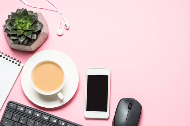 Posto di lavoro ufficio con blocco note, tazza di caffè e tastiera su sfondo rosa
. - Foto, immagini