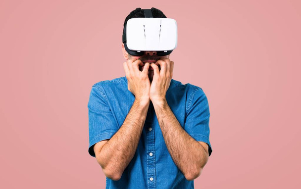 Красивий чоловік з блакитною сорочкою використовує окуляри VR на рожевому фоні
 - Фото, зображення