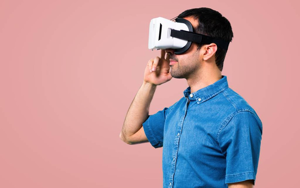 Красивый мужчина в синей рубашке с помощью очков VR на розовом фоне
 - Фото, изображение