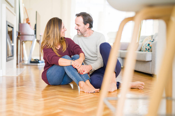 Beautiful romantic couple sitting together on the floor at home - Фото, изображение