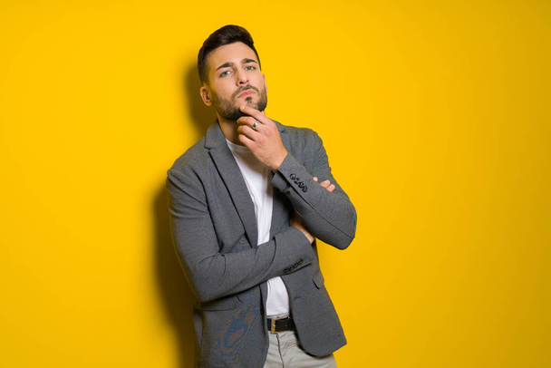 Joven hombre guapo posando y modelando sobre fondo aislado amarillo
 - Foto, Imagen